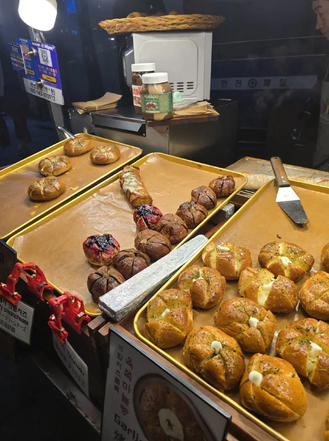 A stall with three trays of bread rolls with various toppings