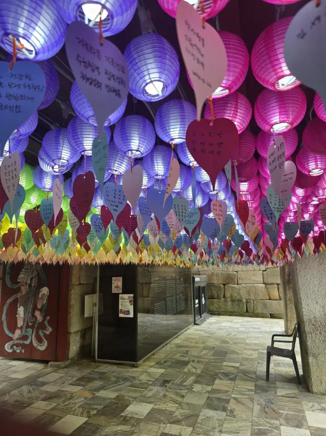 A ceiling covered in colourful paper lanterns with messages on heart shaped paper hanging from them