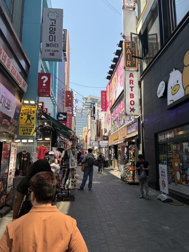 A street with stores either size with people standing in the street