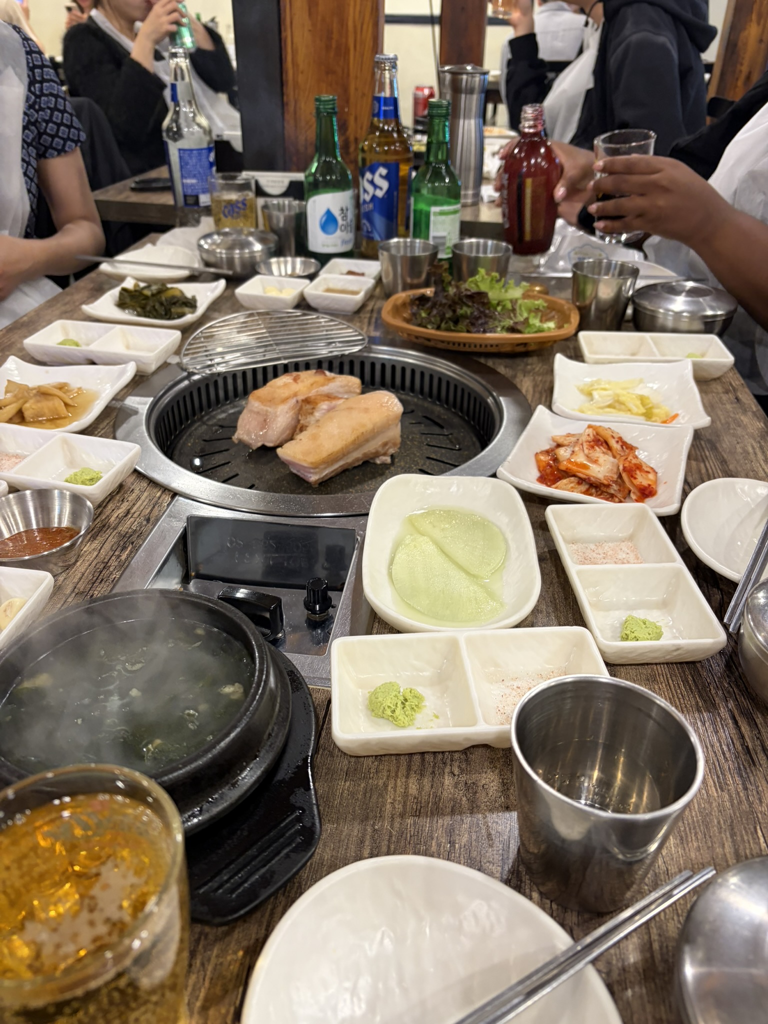 Our first Korean BBQ Many plates with food sitting on a wooden table with an open grill plate in the middle