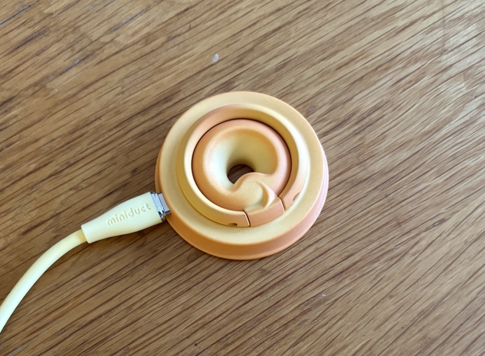 A 'magsafe' charger and pop-socket A round magsafe charger lying on a wooden table that looks like a butter biscuit