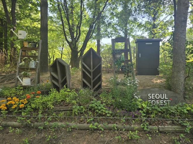 A flower bed with a various wooden shelves and the text 'Seoul Forest' on a wooden board