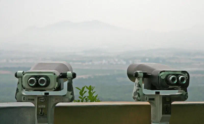 Two pairs of binoculars on poles look out over a misty landscape
