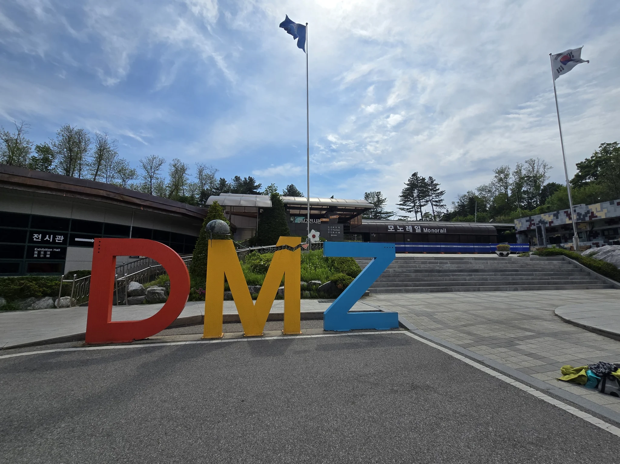 The sign at the center of the DMZ A multicoloured sign of the letters ‘DMZ’ in front of a monorail station