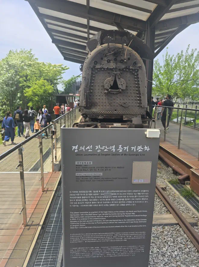 An informational sign with a rusted train in the background