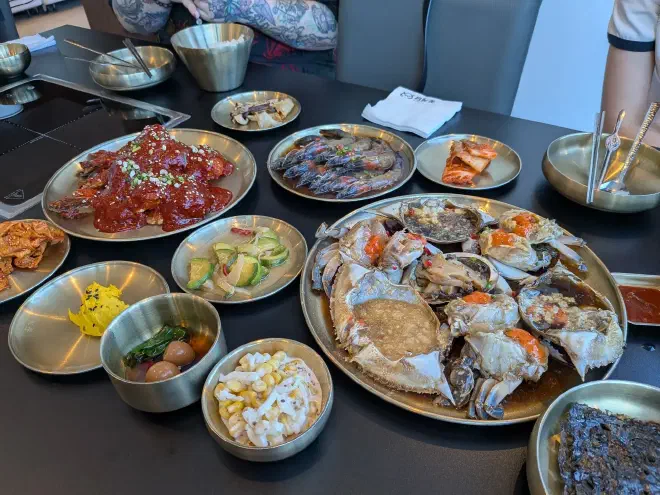 Our marinated crab meal Multiple metal plates on a black table with various colourful foods on them