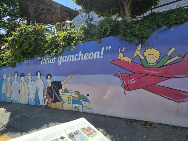 A hand painted wall depicting a kpop group and 'The Little Prince'