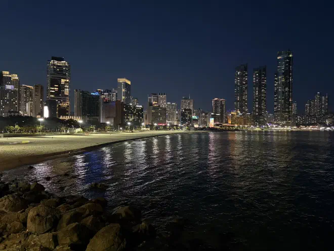 A night time view of a city skyline with a beach