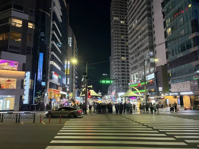 People waiting at a pedestrian crossing in Busan A wide pedestrian crossing with people waiting and tall buildings in the background