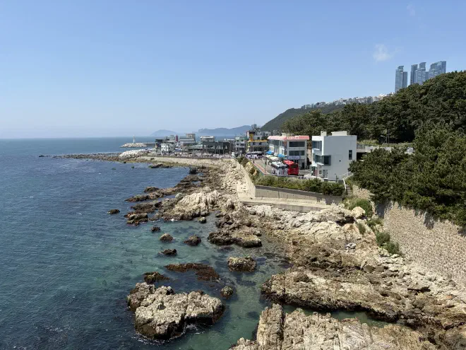 A rocky beach next to the ocean with several buildings along its edge