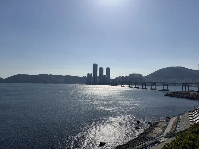 Busan across the ocean A calm ocean with high rise buildings in the background