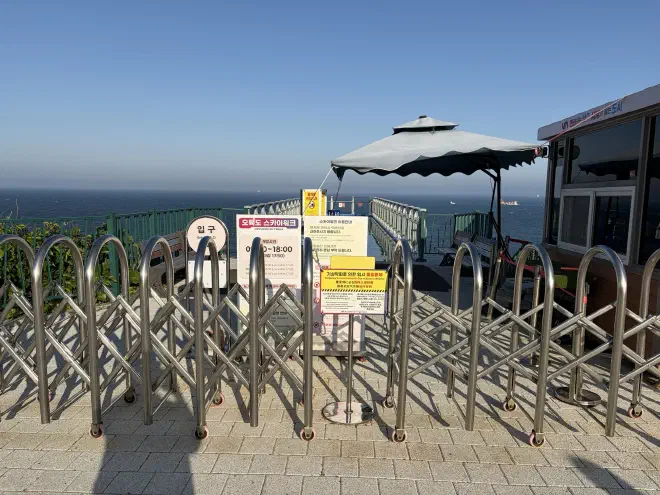 The Oryukdo Skywalk was closed A metal barricade pulled across a path with multiple signs on it