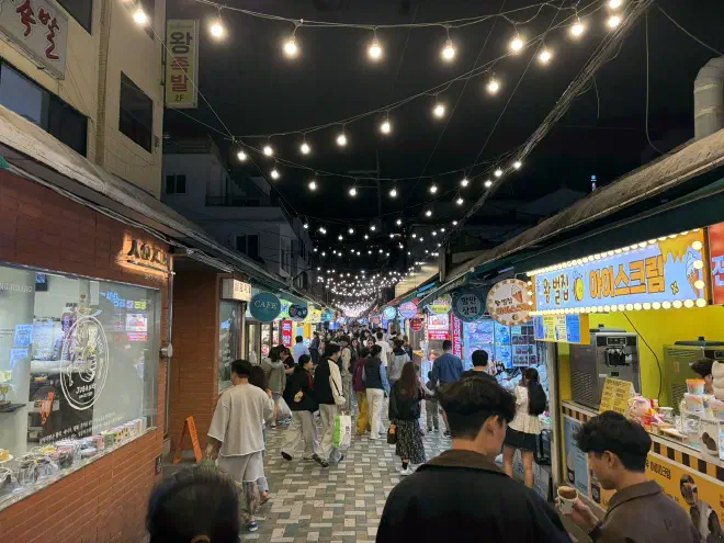 A Busan night market A narrow street adorned with string-lights, packed with people