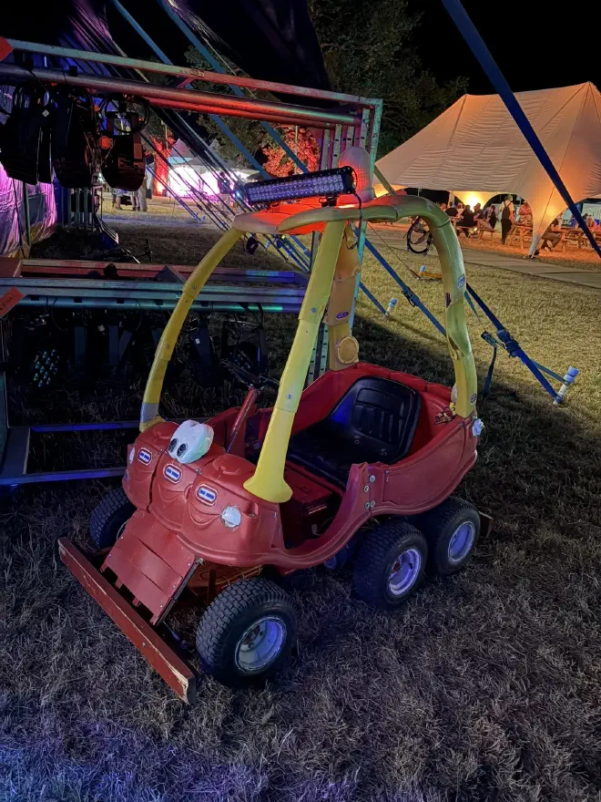 A Little Tikes Cozy Coupe which has been modified to sit an adult and has offroad wheels