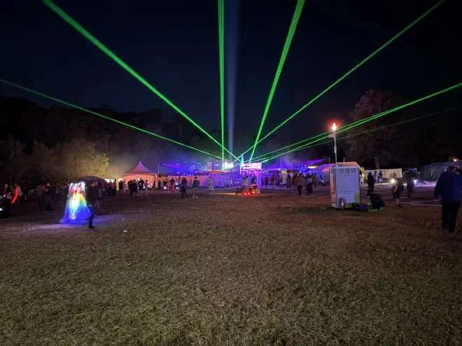 Green lasers shoot into the sky from a building at night