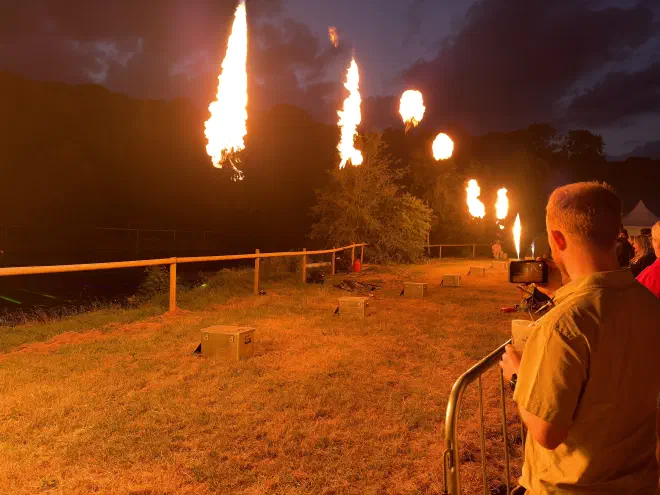 Flames shoot from metal boxes while people look on