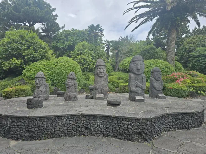 Five stone statues which resemble men with hats sit on top of a raised stone platform