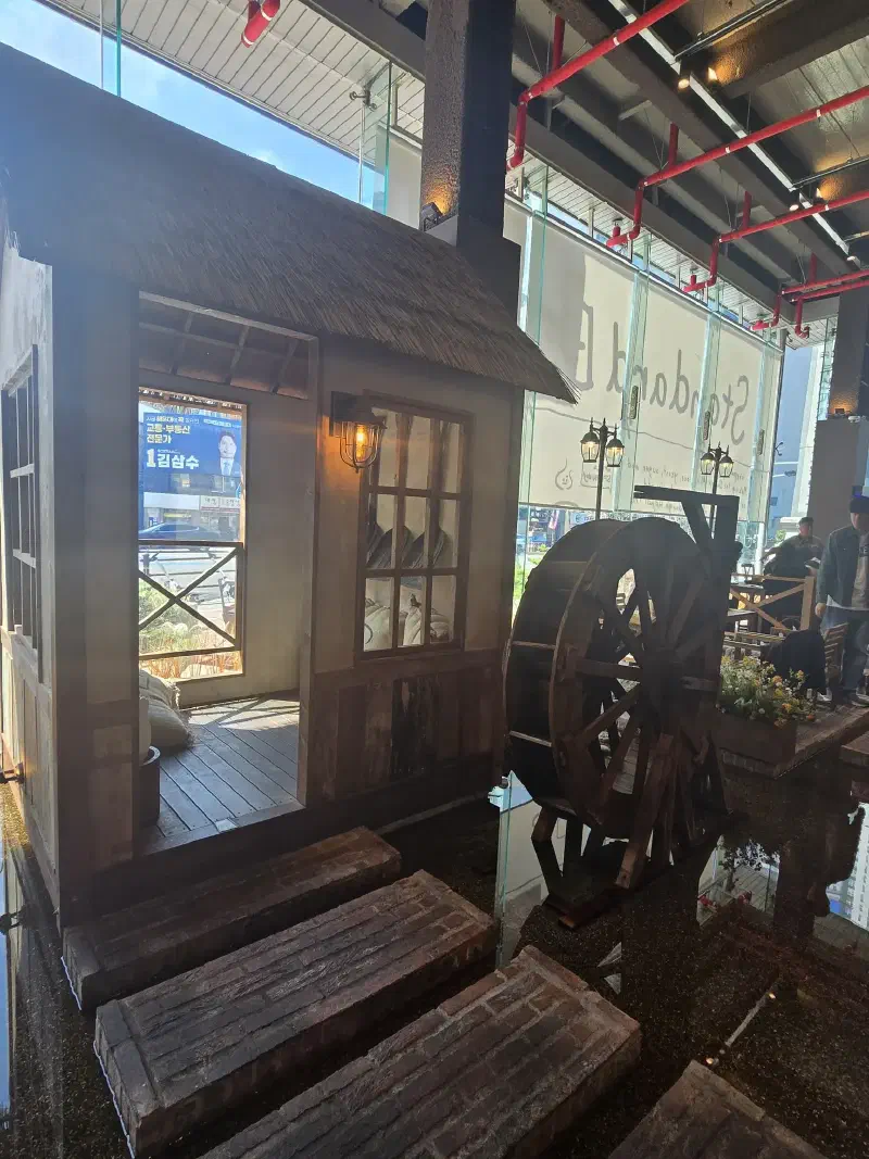 The inside of a building with stone steps leading to a small hut with a waterwheel next to it