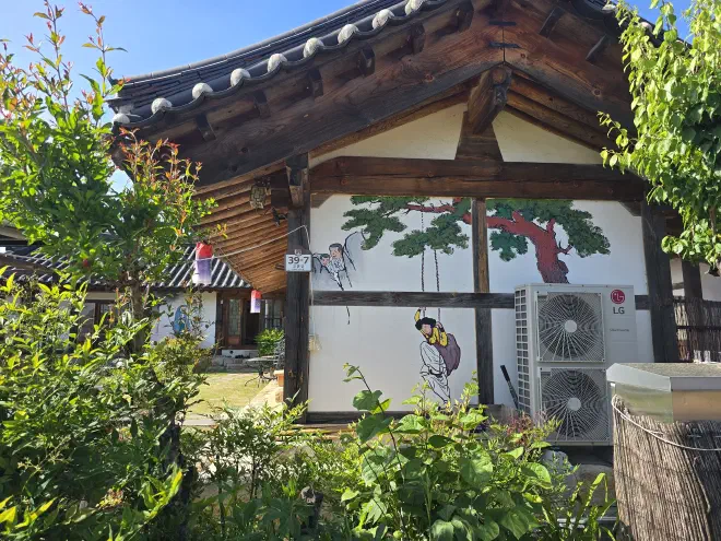 A traditional korean building with two air-conditioners has a tree and woman in a swing painted on its side