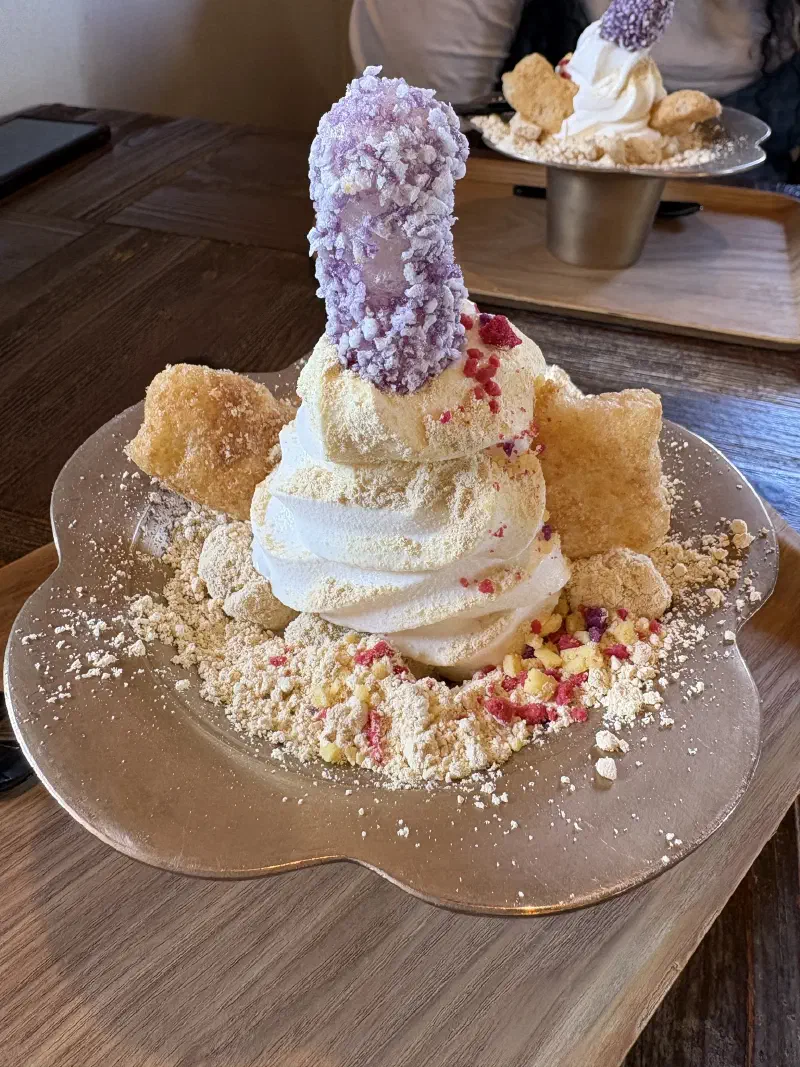 A purple phallic-shaped Injeolmi rice cake sits on ice-cream on a metal bowl
