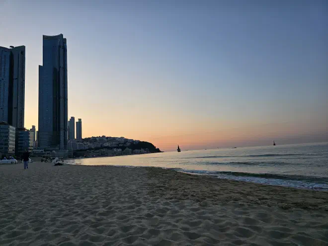 Sun rises in the distance behind two high-rise buildings