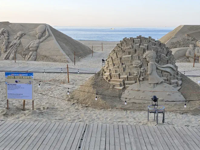 A sand sculpture with a representation of the Little Prince with the ocean in the background
