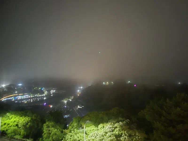 Nighttime view through thick fog revealing scattered city lights below