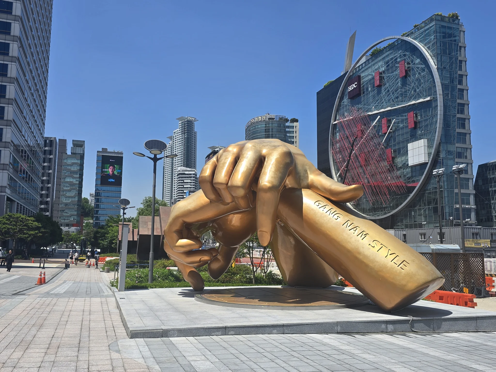 Giant Gangnam Style A statue of giant golden hands sits between tall glass buildings