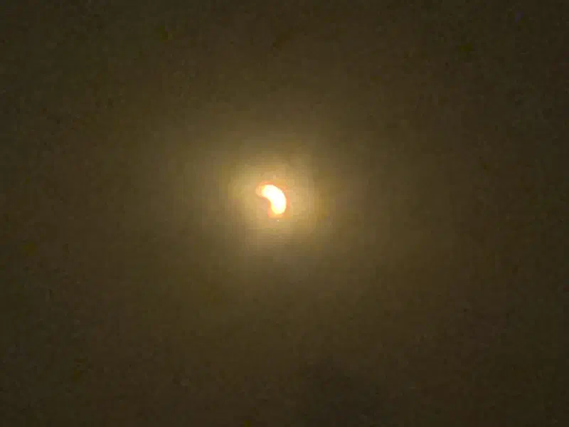 A grainy image of a crescent sun