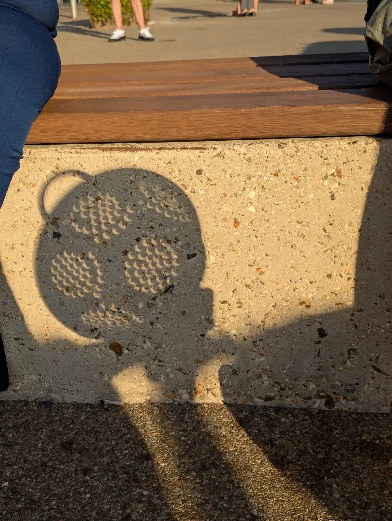 A colander projecting cresent suns onto a stone bench